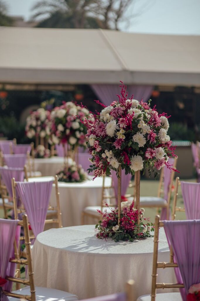 Chic wedding setup with floral centerpiece and lavender chairs outdoors.